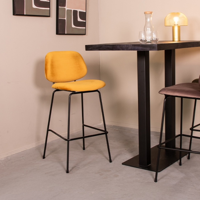 Barkruk met rugleuning Bram in okergeel velvet aan een bartafel