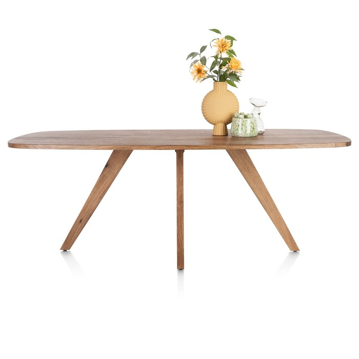 Deens ovale eettafel Everest in mangohoutfineer op schuine houten poten, zijaanzicht met gele vaas en bloemen op het blad