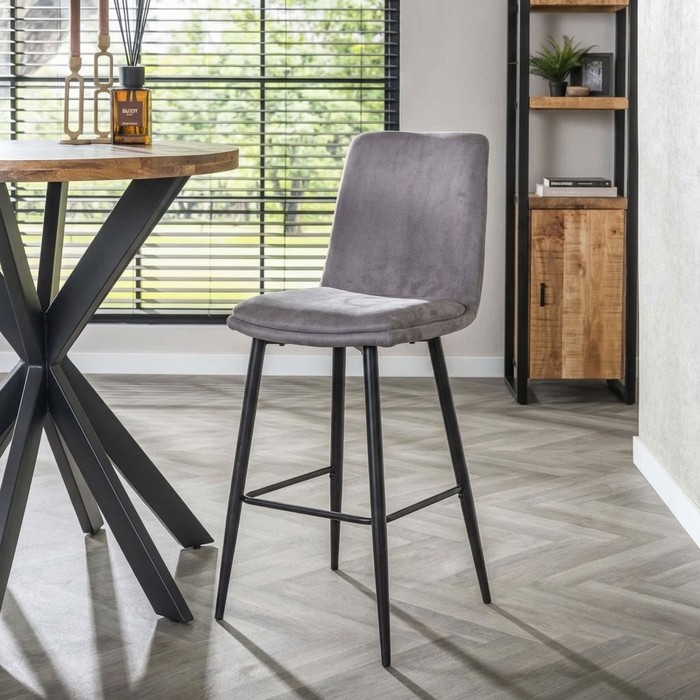 Grijze barkruk in een industrieel interieur met mangohouten kast