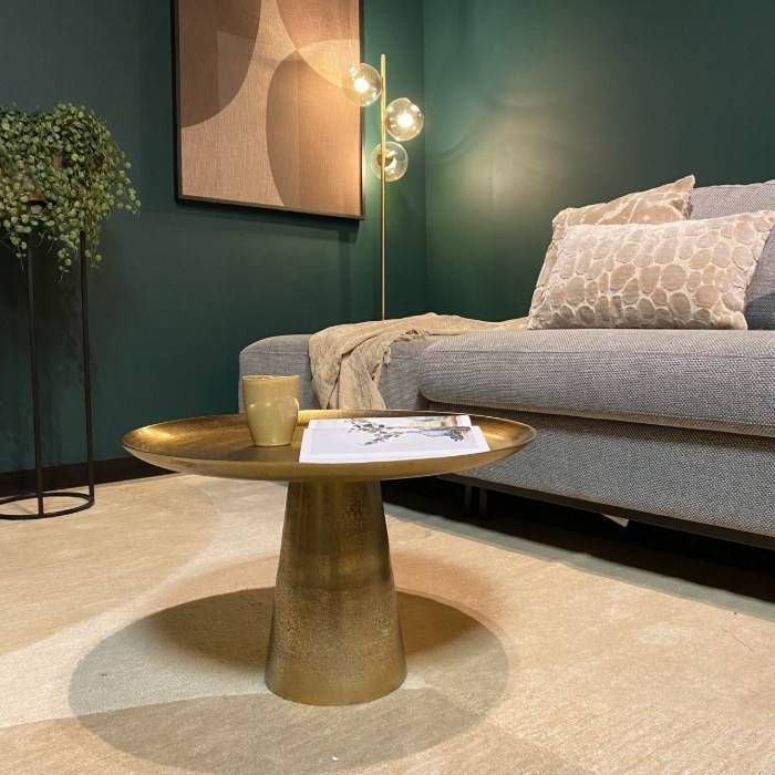 Gouden salontafel Daisy Large met open boek in een groene woonkamer