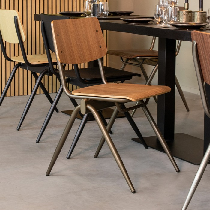 Stapelbare stoel Sven in walnoot houtlook met goudkleurig frame aan de eettafel