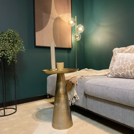 Ronde gouden bijzettafel Daisy 40 cm naast een bank in een groene woonkamer
