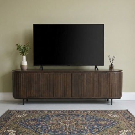 Sfeerfoto van een tv-meubel in walnoot met ronde hoeken van 170 cm in een woonkamer, met een televisie erop, een vaas met plant en wierookstokjes