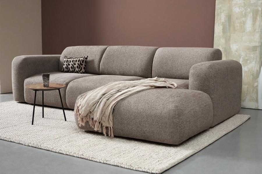 Taupe modulaire hoekbank met plaid op een wollen vloerkleed