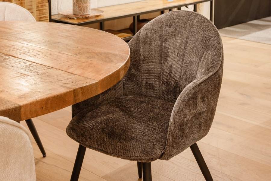 Bruine stoffen eetkamerstoel aan een ronde mangohouten eettafel