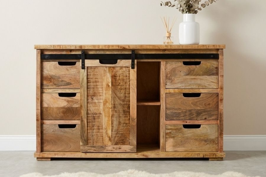 Mangohouten dressoir met schuifdeur en zes laden tegen een lichte muur