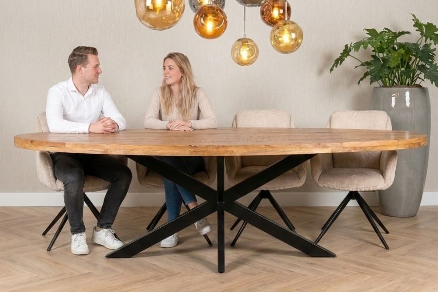 Man en vrouw aan een grote ovale eettafel met zwarte spinpoot